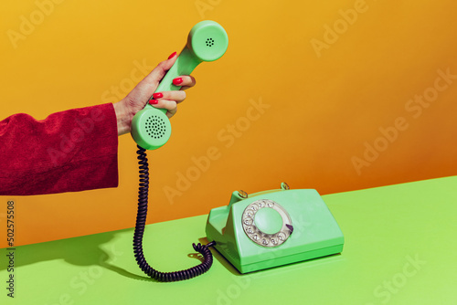 Фотография Colorful bright image of female hand holding old-fashioned green colored phone,