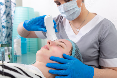 Young woman receiving electric galvanic anti-aging face spa massage at beauty salon. photo