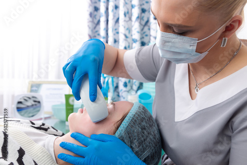 Young woman receiving electric galvanic anti-aging face spa massage at beauty salon. photo