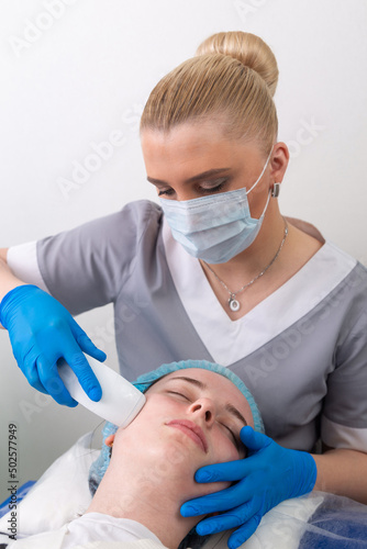 Young woman receiving electric galvanic anti-aging face spa massage at beauty salon. photo