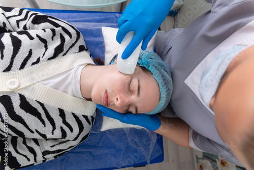 Young woman receiving electric galvanic anti-aging face spa massage at beauty salon. photo