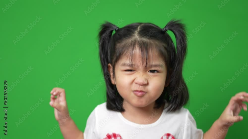 Portrait of happy and funny Asian child girl on green screen background, a child looking at camera. Preschool kid dreaming fill with energy feeling healthy and good concept
