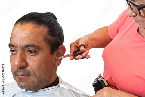 Close-up of young Latin man while a woman's hand cuts the hairs of the ears with scissors