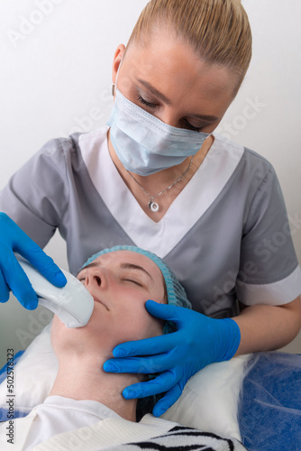Young woman receiving electric galvanic anti-aging face spa massage at beauty salon. photo