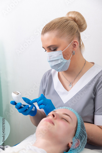 The cosmetologist adjusts the power of the device for galvanic massage. photo