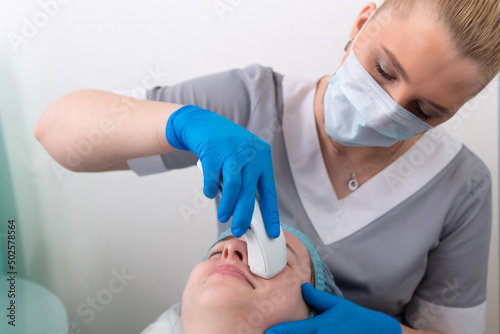 Young woman receiving electric galvanic anti-aging face spa massage at beauty salon. photo