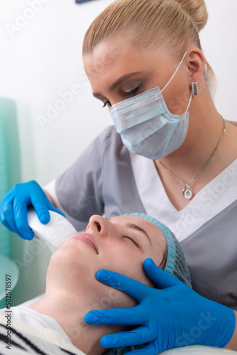 Young woman receiving electric galvanic anti-aging face spa massage at beauty salon. photo