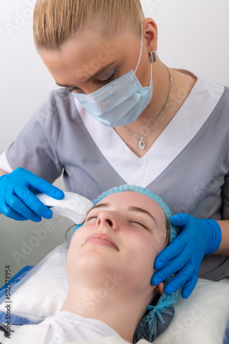 Young woman receiving electric galvanic anti-aging face spa massage at beauty salon. photo