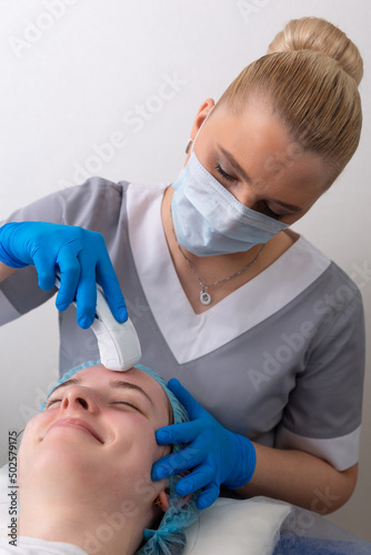 Young woman receiving electric galvanic anti-aging face spa massage at beauty salon. photo