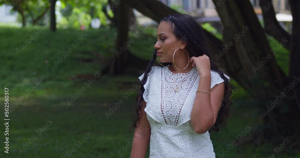 Camera pan left while a young girl plays in her hair while wearing large hoop earings Camera pan left while a young girl plays in her hair while wearing large hoop earings