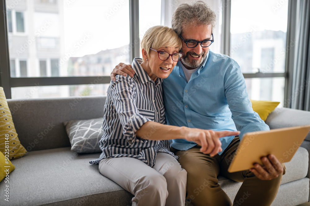 Happy smiling mature couple using digital tablet at home Happy smiling mature couple using digital tablet at home