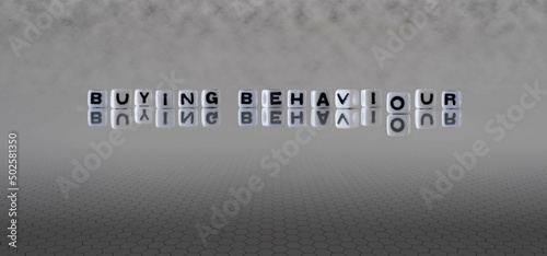 buying behaviour word or concept represented by black and white letter cubes on a grey horizon background stretching to infinity