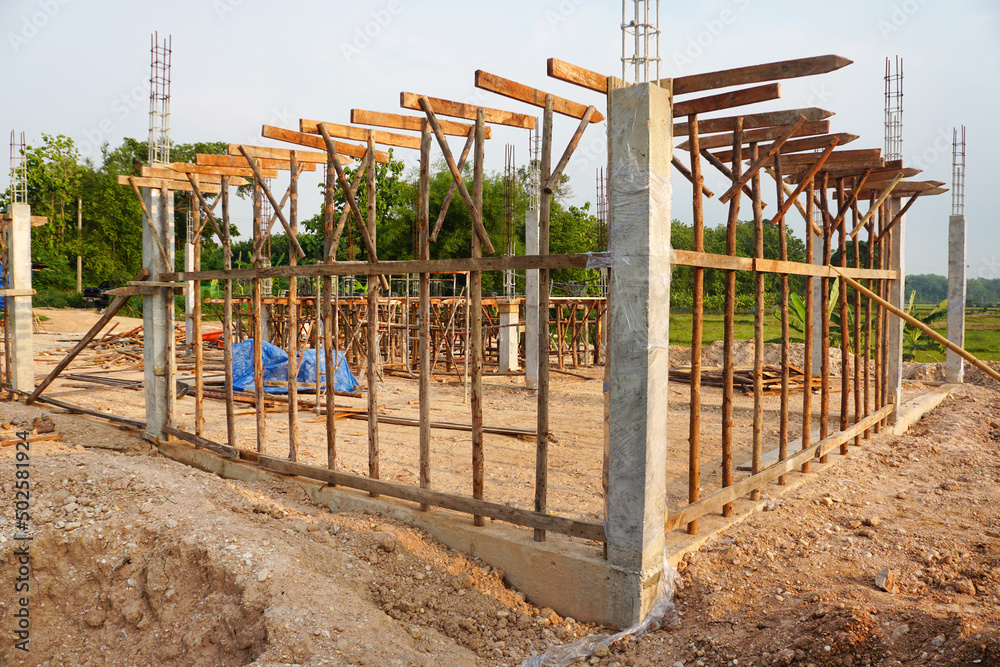 Temporary poles and wooden scaffolding supports a concrete beam at the house construction site.