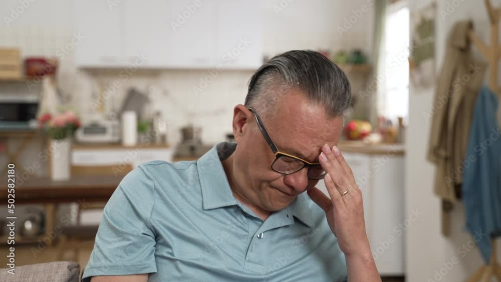 closeup of stressed asian elderly male worrying about problem alone at home. he props his head while thinking hard for solutions