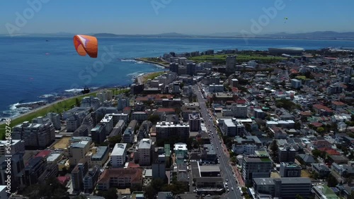 Drone shot of Sea Point, Cape Town - drone is reversing, watching paragliders coming down from Signal Hill. Snippet could ideally be used for travel related videos or Cape Town movies.