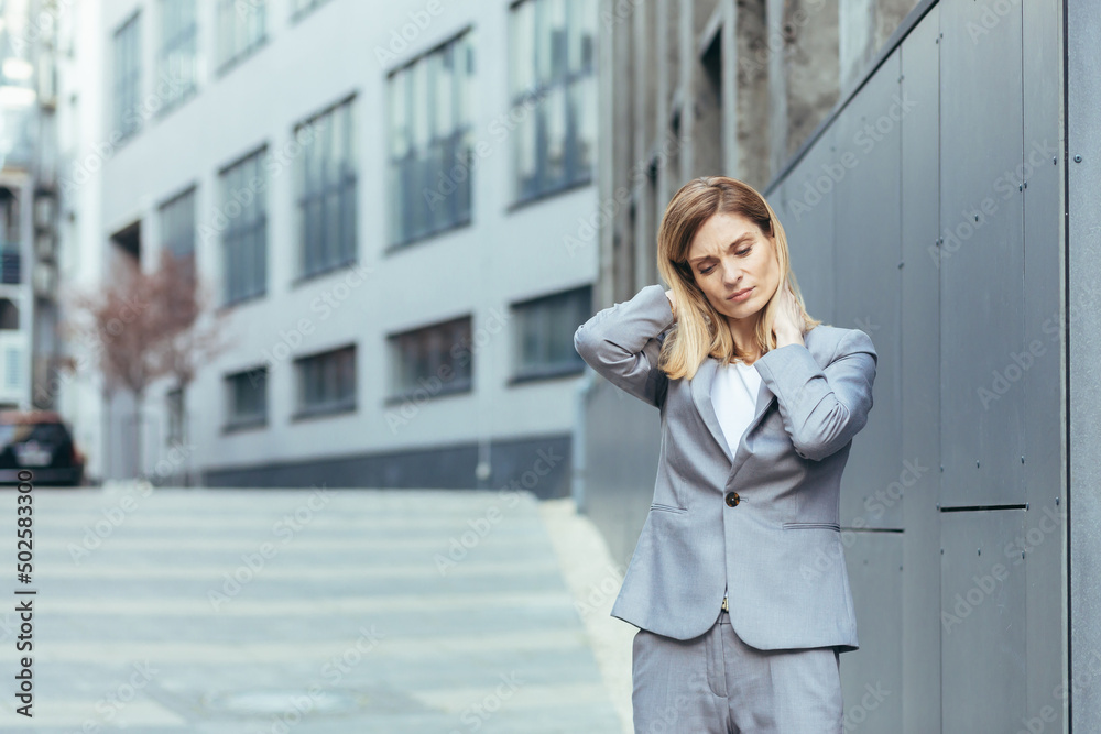 Fototapeta premium Woman near the office has severe back and neck pain, fatigue and depression of a business woman from the outside