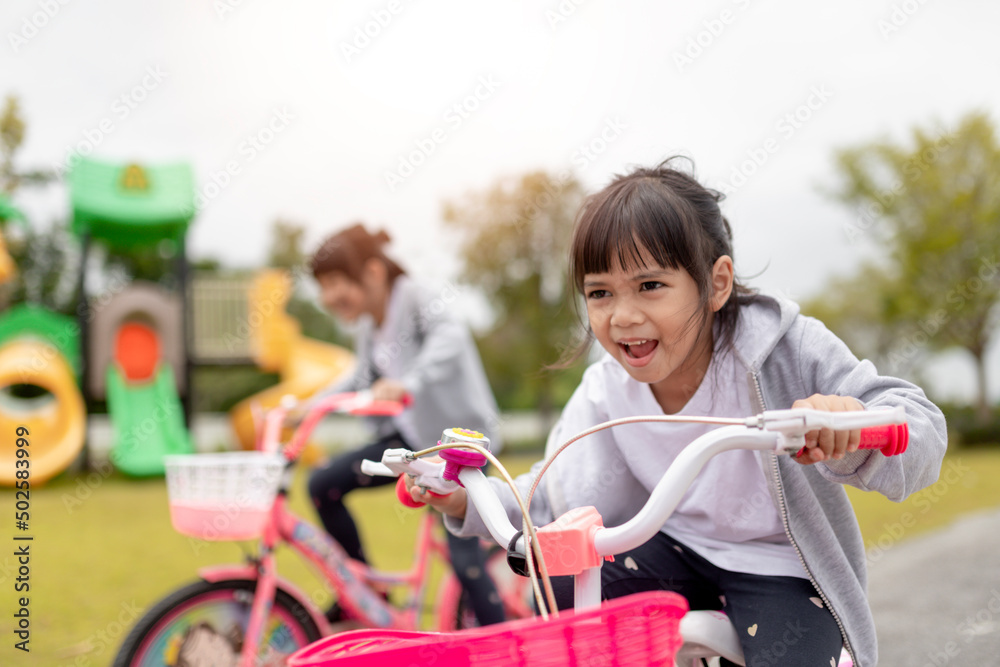 Obraz premium happy cheerful child girl riding a bike in Park in the nature