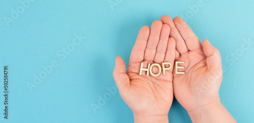 Holding the word hope in the palm of the hands, trust and believe concept, having faith in the future, hopeful positive mindset
