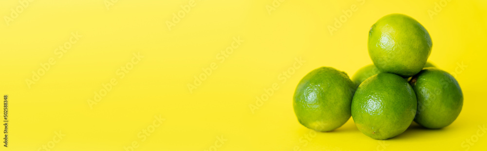 Juicy limes on yellow surface with copy space, banner Juicy limes on yellow surface with copy space, banner