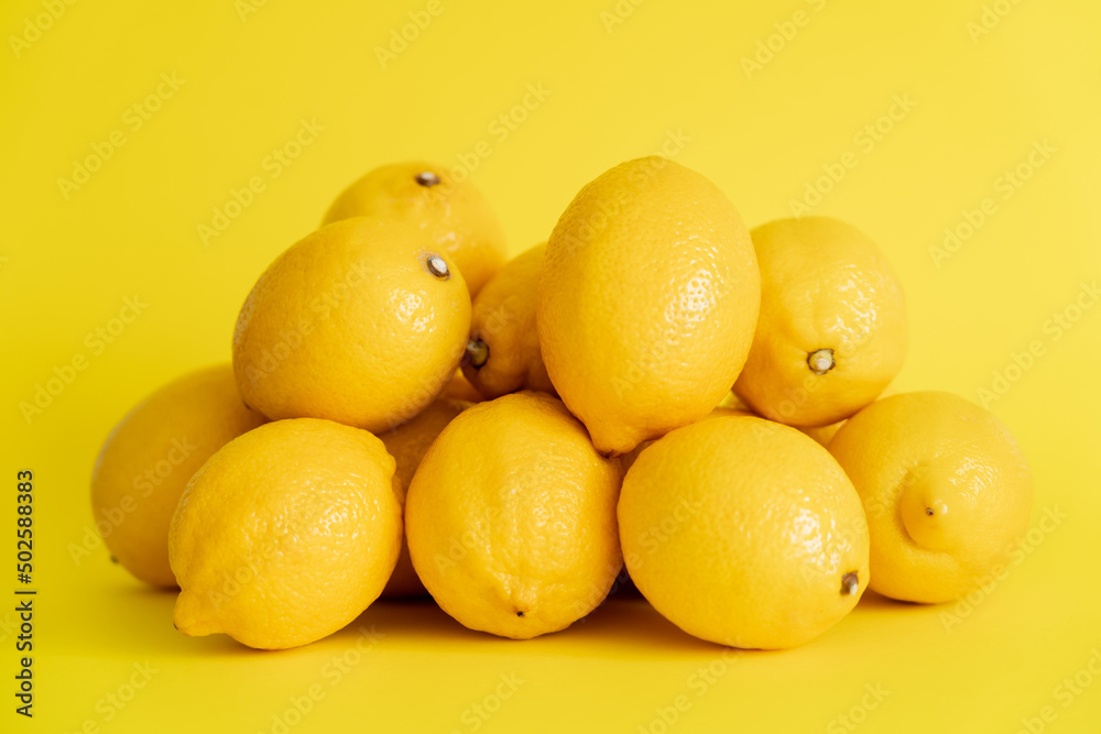 Heap of fresh lemons on yellow surface Heap of fresh lemons on yellow surface