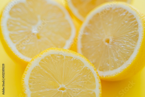 Close up view of blurred halves of lemons on yellow surface