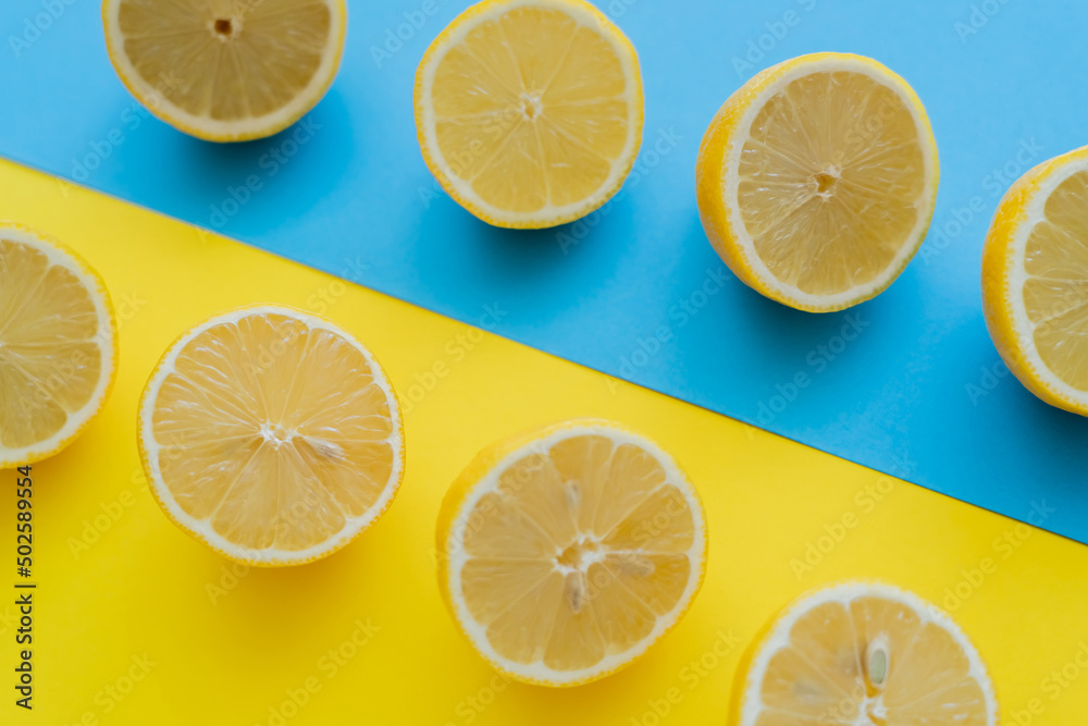 Top view of fresh cut lemons on blue and yellow background