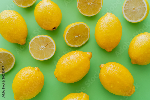 Top view of wet lemons on green background