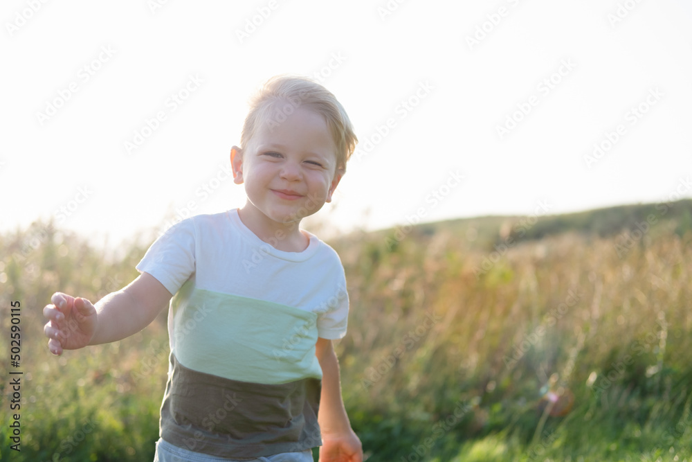 smiling kid blond boy with in nature in a windy and sunny day smiling kid blond boy with in nature in a windy and sunny day