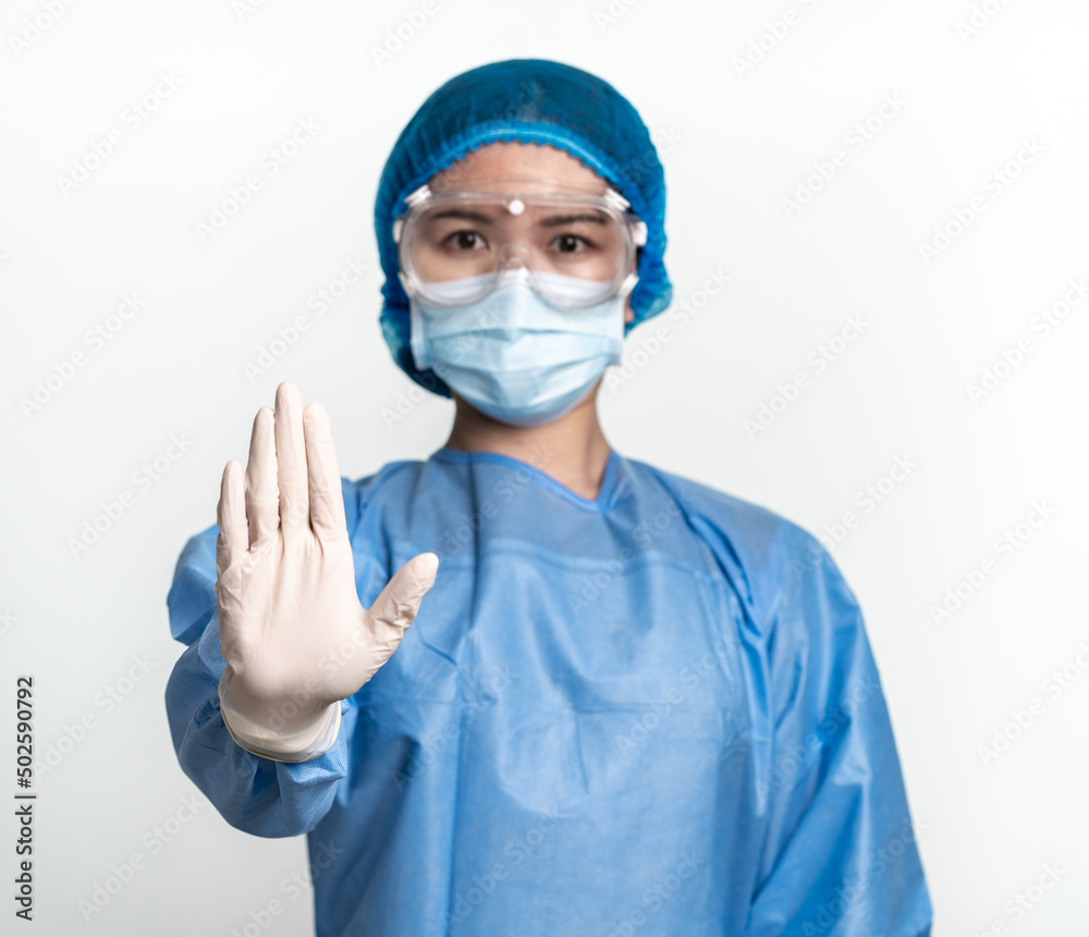 Doctor or nurse wearing protective suit and mask showing stop gesture on the white background. Doctor or nurse wearing protective suit and mask showing stop gesture on the white background.