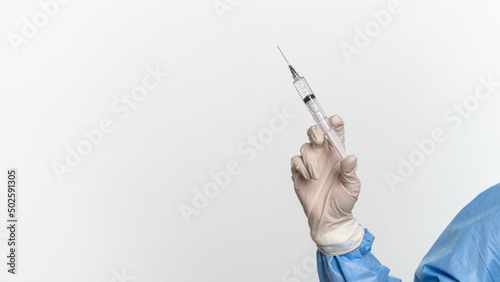 Doctor or nurse wearing protective suit and mask is holding a disposable injector 
