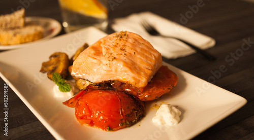 simmered slice of salmon with tomato spinon and coconut sauce on a white plate photo