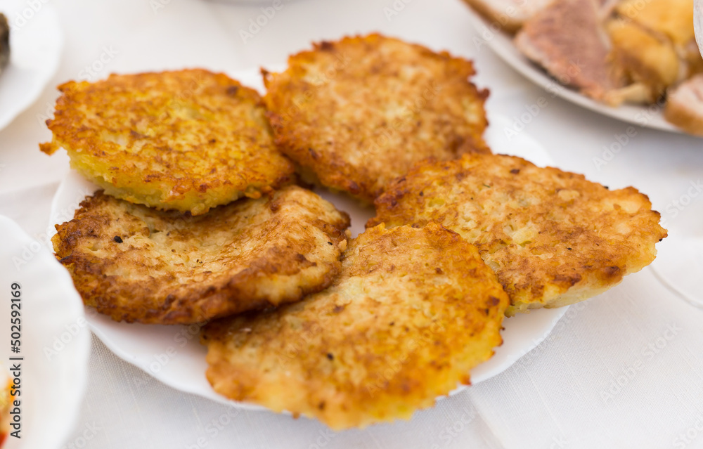 Fried grated potato pancakes with sour cream on white plate Fried grated potato pancakes with sour cream on white plate