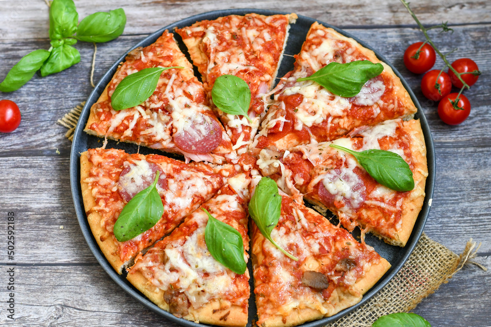 Close up of classic Italian Pizza with Ham and salami . Fresh basil,tomato sauce ,mozzarella cheese , mushrooms and green peppers Close up of classic Italian Pizza with Ham and salami . Fresh basil,tomato sauce ,mozzarella cheese , mushrooms and green peppers