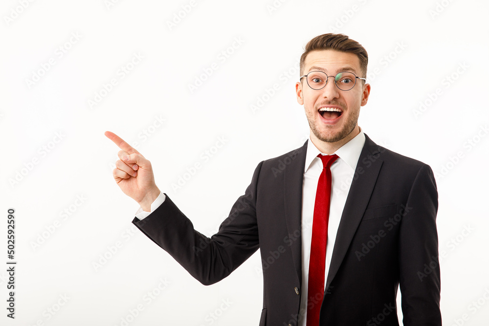 A young businessman in a business suit points to copyspace. A young businessman in a business suit points to copyspace.