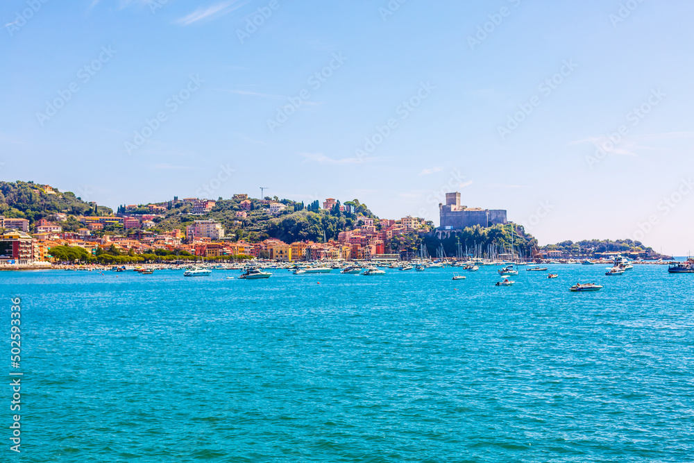 Fishing boats moored on water in harbor of Ligurian and Mediterranean Sea near coastline of Riviera di Levante of National park Cinque Terre Coast with blue sky, Riomaggiore village, Liguria, Italy.