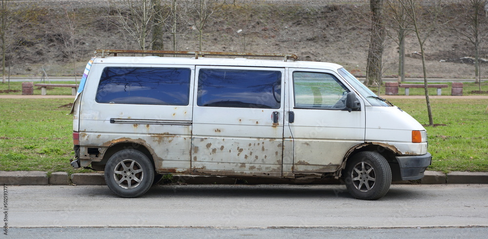 Old rusty white minivan parked on the road, Granitnaya Street, St. Petersburg, Russia, May 2022