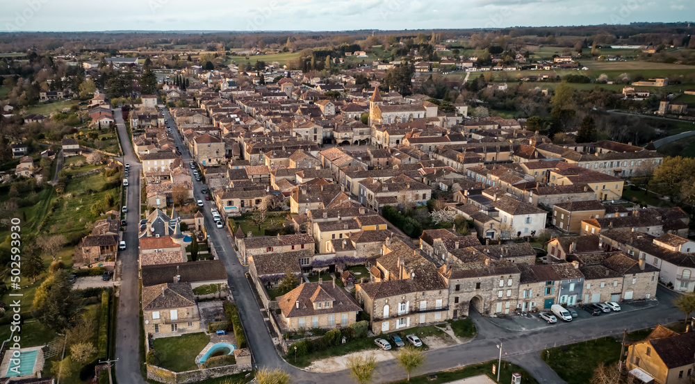 Wide drone shot of the beautiful bastide village of Monpazier in Périgord at sunset, Dordogne