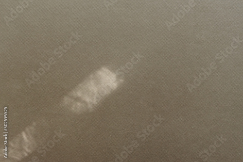 Top view flat lay background with organic shadows, bokeh, and texture on a brown colored kraft paper background. Minimal summer lights and shadow concept.