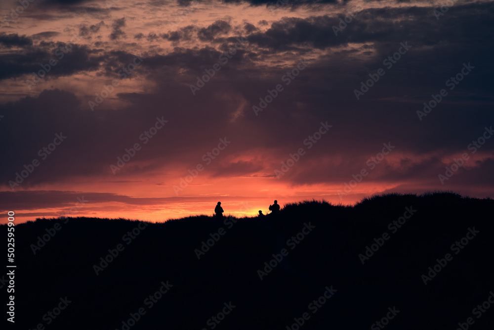 people standing on top of the dunes at sunset. High quality photo