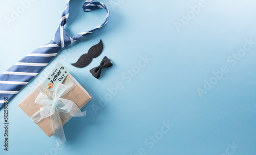 Photo Happy Fathers Day background concept with gift box, decorated bow tie, necktie and mustache on bright pastel background