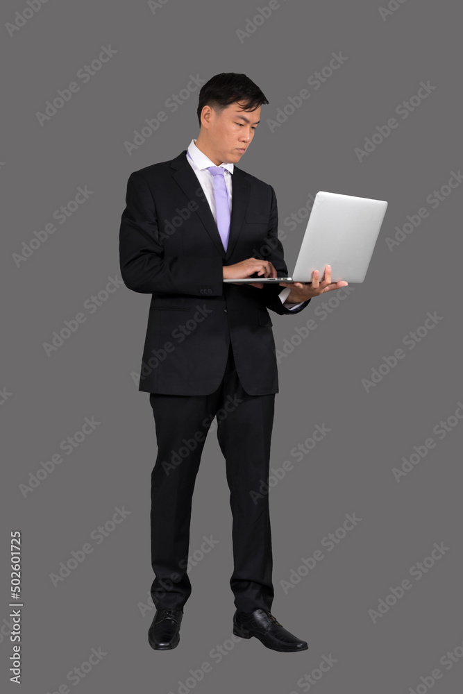 A businessmanwho works uses a laptop. while standing on a gray background