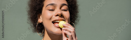 pleased african american woman eating yellow candy, banner
