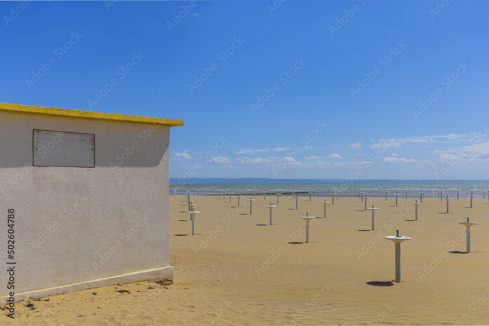 Obraz premium Panoramic view to Grado Adriatic sea beach with tiny white building under blue sky on sunny spring day