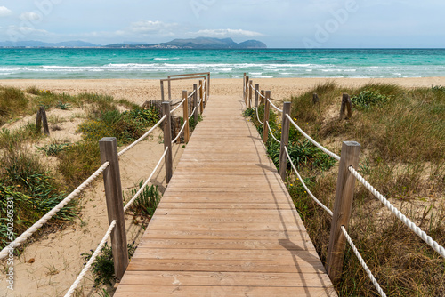 Mallorca island. Windy day at Playa del Muro. Wooden road to the sea