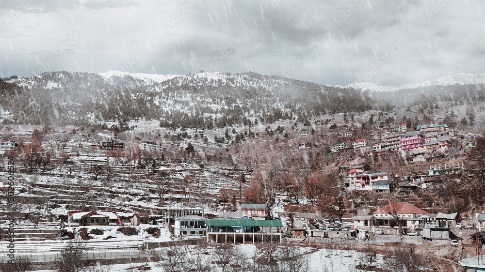 View of a village in mountains during snowfall.