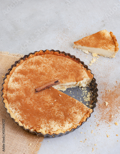 Traditional South African milk tart freshly baked and in tin. Mottled grey and rustic surface with copy space photo