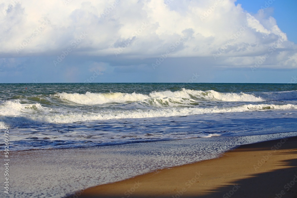 Marine seascape with bright blue sky and the ocean with white waves. Deep blue sea and white clouds on the horizon. Tropical sea of Trancoso, Bahia, Brazil