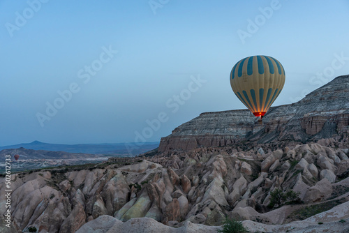 A lonely hot air balloon flying over the valley Cappadocia in the background.