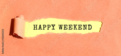 The text HAPPY WEEKEND appearing on yellow paper behind torn color paper. Top view.