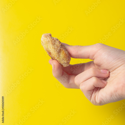 Holding a fried snack chicken nuggets on an yellow background in your hand